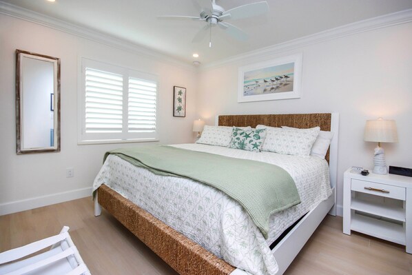 Un dormitorio con cama, mesita de noche y ventilador de techo.