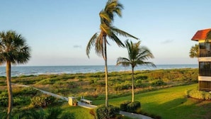 A coastal property with a pathway leading to a bench, a barbecue grill, and palm trees. - Stylish 3rd floor condo on Sanibel Island with ocean views - Sandalfoot 4D3 (Sanibel Island)
