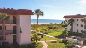 A hotel with a view of the beach, featuring multiple floors, balconies, and a pathway leading to the beach. - Stylish 3rd floor condo on Sanibel Island with ocean views - Sandalfoot 4D3 (Sanibel Island)