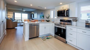 A modern kitchen with white cabinets, stainless steel appliances, and a large island.