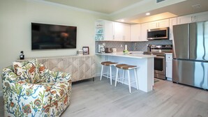 Une cuisine moderne avec des meubles blancs, des appareils en acier inoxydable et un coin bar équipé de tabourets.