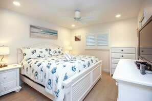 A bedroom with a bed, nightstands, a dresser, and a ceiling fan.