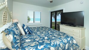 A bedroom with a bed, a television, a dresser, and a window with a view of the ocean. - 3rd Story Sanibel condo with panoramic views of the Gulf - Sandalfoot 5C3 (Sanibel Island)