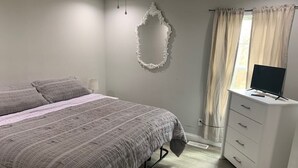 Un dormitorio con cama, cómoda, espejo y televisión.
