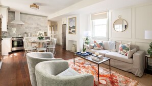 Un salon spacieux comprenant un canapé, deux fauteuils, une table basse et un coin repas avec des chaises et une table.