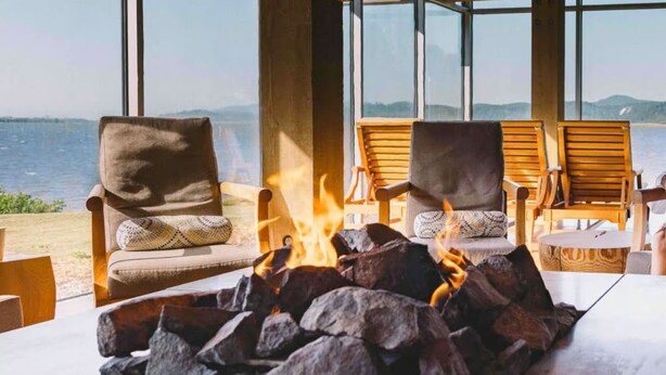 A cozy outdoor seating area with a fire pit, wooden chairs, and a view of the sea. - Coast & Course  *Adventure Basecamp*Beach Access* (Lincoln Beach)