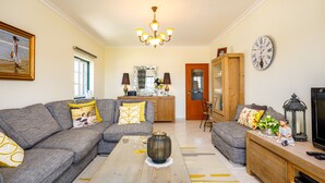A living room with a sectional sofa, a coffee table, a wooden cabinet, and a television.
