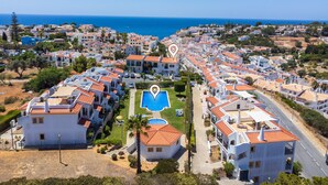A coastal residential area with white buildings, a swimming pool, and a view of the sea.
