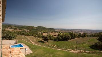 Vista de un paisaje montañoso con piscina y un edificio de techo con tejas.