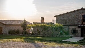 A stone building with a tiled roof, a small tower, and a well-maintained garden. - Country House 'La Cajola' with Mountain View, Private Pool and Wi-Fi (Lladurs)