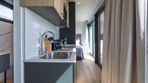 A modern kitchen with a built-in sink, wooden cabinets, and a view to the living area. - Bungalow '2 Con Piscina En La Playa' with Sea View, Wi-Fi and Air Conditioning (A Pobra do Caramiñal)
