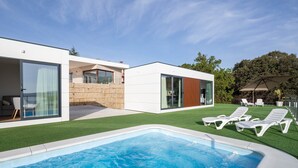A modern house with a swimming pool, glass doors, and a patio with lounge chairs. - Bungalow '2 Con Piscina En La Playa' with Sea View, Wi-Fi and Air Conditioning (A Pobra do Caramiñal)