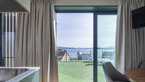 A modern room with a large sliding glass door leading to a grassy outdoor area, a built-in kitchen counter, and a dining table with chairs. - Bungalow '2 Con Piscina En La Playa' with Sea View, Wi-Fi and Air Conditioning (A Pobra do Caramiñal)