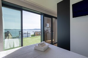 A modern room with a large sliding glass door leading to a balcony with a view of the sea and distant mountains. - Bungalow '2 Con Piscina En La Playa' with Sea View, Wi-Fi and Air Conditioning (A Pobra do Caramiñal)