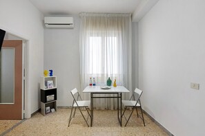 A small room with a white table, two chairs, a bookshelf, and a window with sheer curtains. - Guest House 'Love Stabia' with Private Terrace, Wi-Fi and Air Conditioning (Castellammare di Stabia)