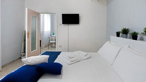 Hotellihuone, jossa on sänky, televisio, työpöytä ja tuoli.