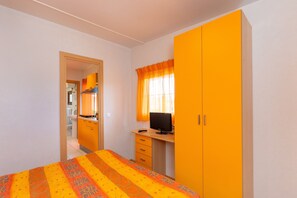 Une chambre à coucher avec un lit, un bureau avec un ordinateur et une armoire.