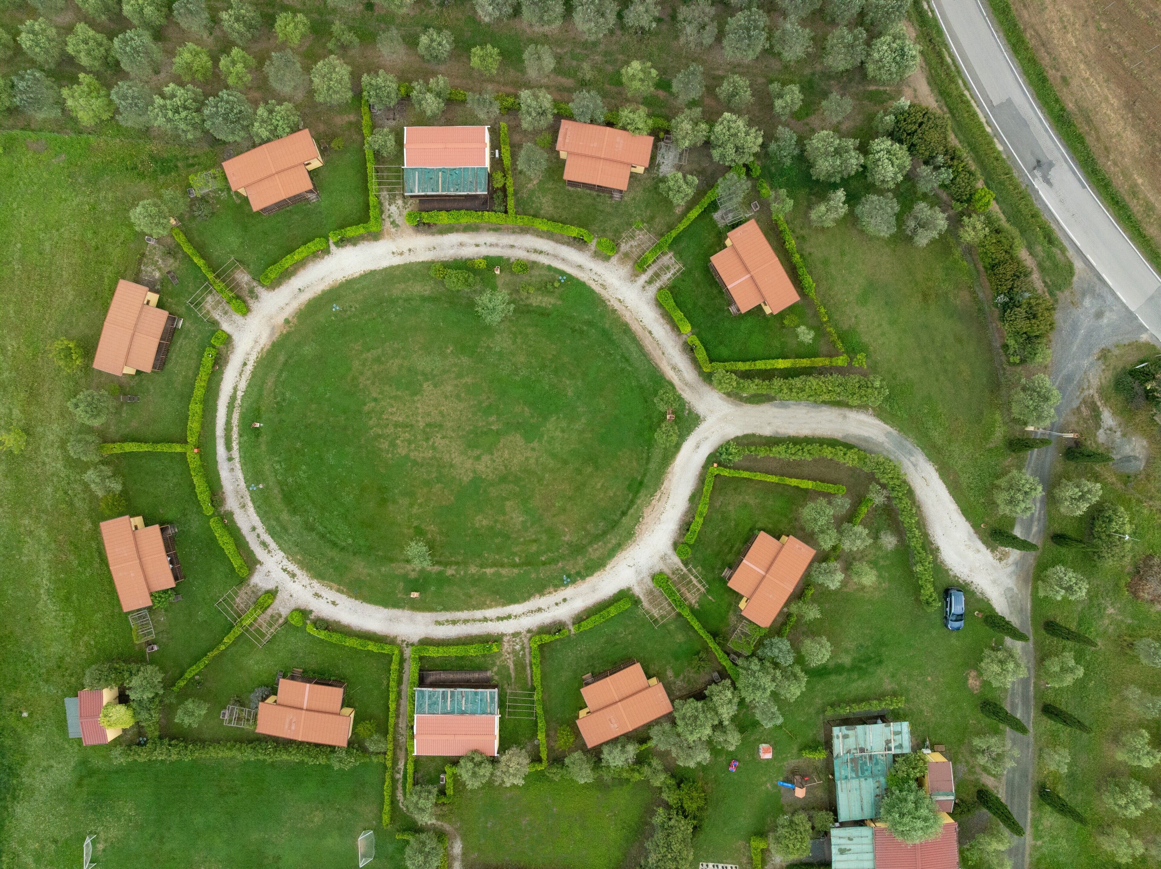 Luchtbeeld van een cirkelvormige indeling met meerdere gebouwen, een groene centrale ruimte en een verbindingsweg.