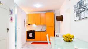 Una cocina moderna con armarios naranjas, una mesa de comedor de vidrio y un bol con limones.