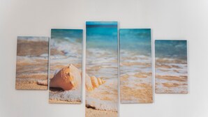 Un muro con cinco paneles que muestran una escena de playa.
