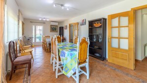 A dining area with a table covered in a patterned tablecloth, surrounded by wooden chairs. - Holiday Home 'Villa Pilara - Brunete' with Private Pool, Wi-Fi and Air Conditioning (Brunete)