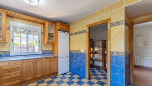 A kitchen with wooden cabinets, a white refrigerator, and a checkered floor. - Holiday Home 'Villa Pilara - Brunete' with Private Pool, Wi-Fi and Air Conditioning (Brunete)