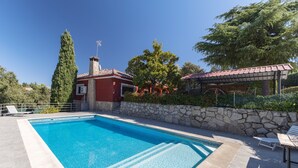 Una piscina rectangular con una pared de piedra y un área de terraza con baldosas.