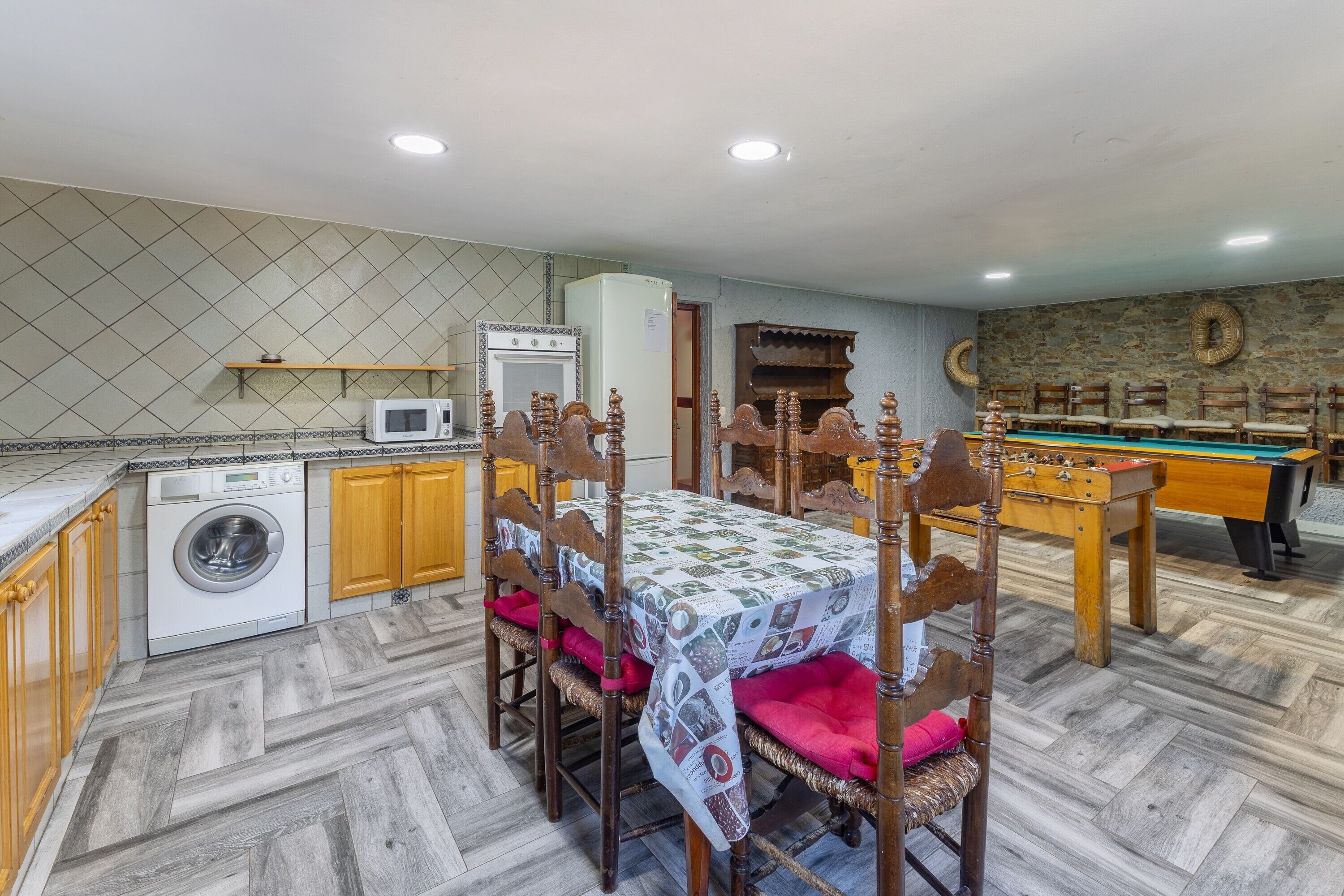 Una cocina compacta con lavadora, una mesa de comedor con sillas y una mesa de billar.