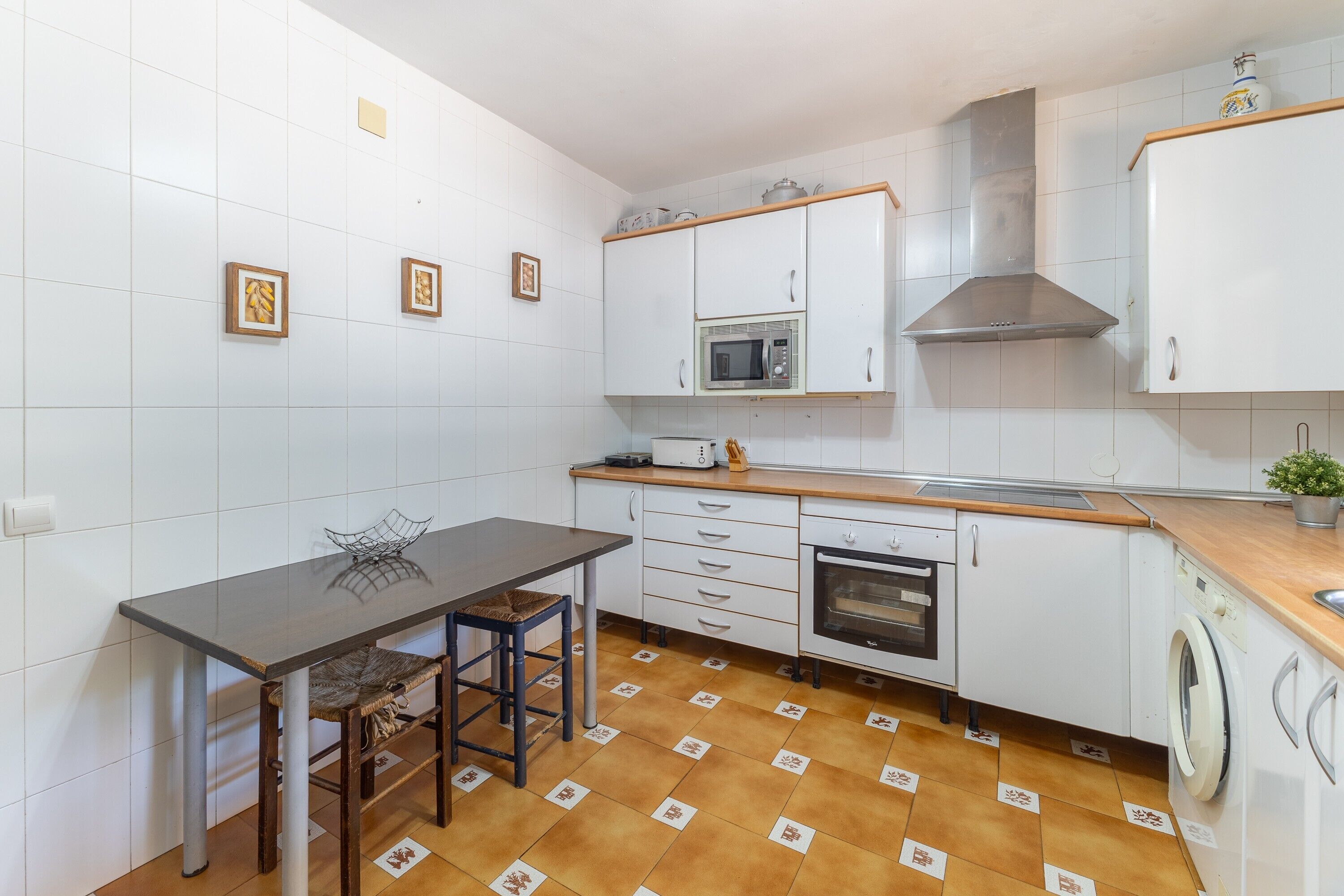 Una cucina compatta con mobili bianchi, un forno a microonde, un forno e una lavatrice.