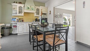 Een moderne keuken met witte kasten, een glazen eettafel en zwarte stoelen.
