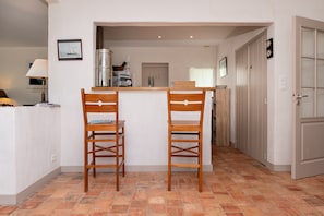 A compact kitchen with two wooden chairs, a small table, and a view into the adjacent dining area.