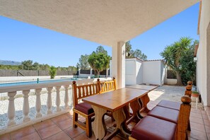 An outdoor patio with a wooden table and benches, a pool, and a view of trees and mountains. - Holiday Home 'Villa Tivissa Avec Piscine' with Sea View, Wi-Fi and Air Conditioning (Les Tres Cales)