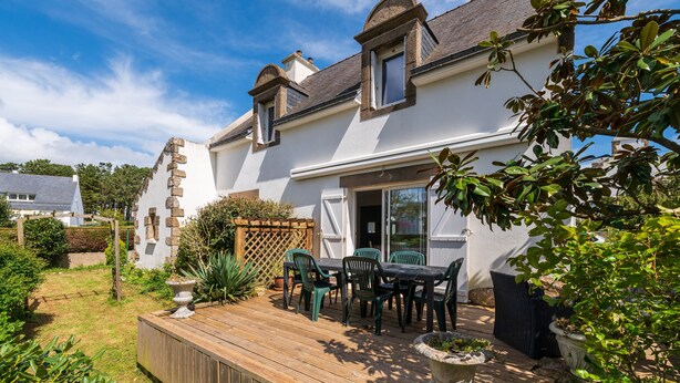 A house with a deck, outdoor furniture, and a garden.