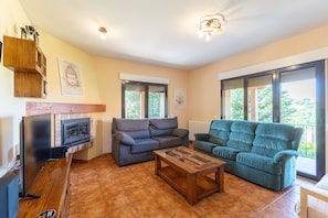 A living room with two sofas, a coffee table, a TV, and a fireplace. - Villa 'Arboleda' with Mountain View, Private Pool and Wi-Fi (La Losa)