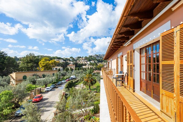 A balcony with wooden railings overlooking a street with parked cars and greenery. - Apartment 'Navarro' with Mountain View, Private Terrace and Wi-Fi (Unknown)