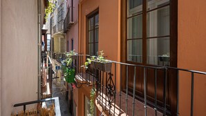 Un stretto vicolo con balconi, un corrimano in metallo e piante in vaso.
