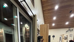 Un pasillo amplio con piso de madera, una puerta de cristal que da al exterior y una zona de cocina con armarios de madera y cubierta.