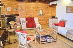 Un salon chaleureux avec une cheminée, des meubles en osier et une table basse.