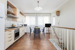 Une cuisine moderne avec un coin repas, un téléviseur et un escalier.