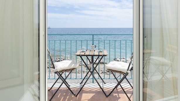 Un balcone con tavolo e due sedie, vista su uno specchio d'acqua.