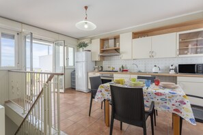 Une cuisine équipée d’une table à manger, de chaises, d’un réfrigérateur et d’un four à micro-ondes.