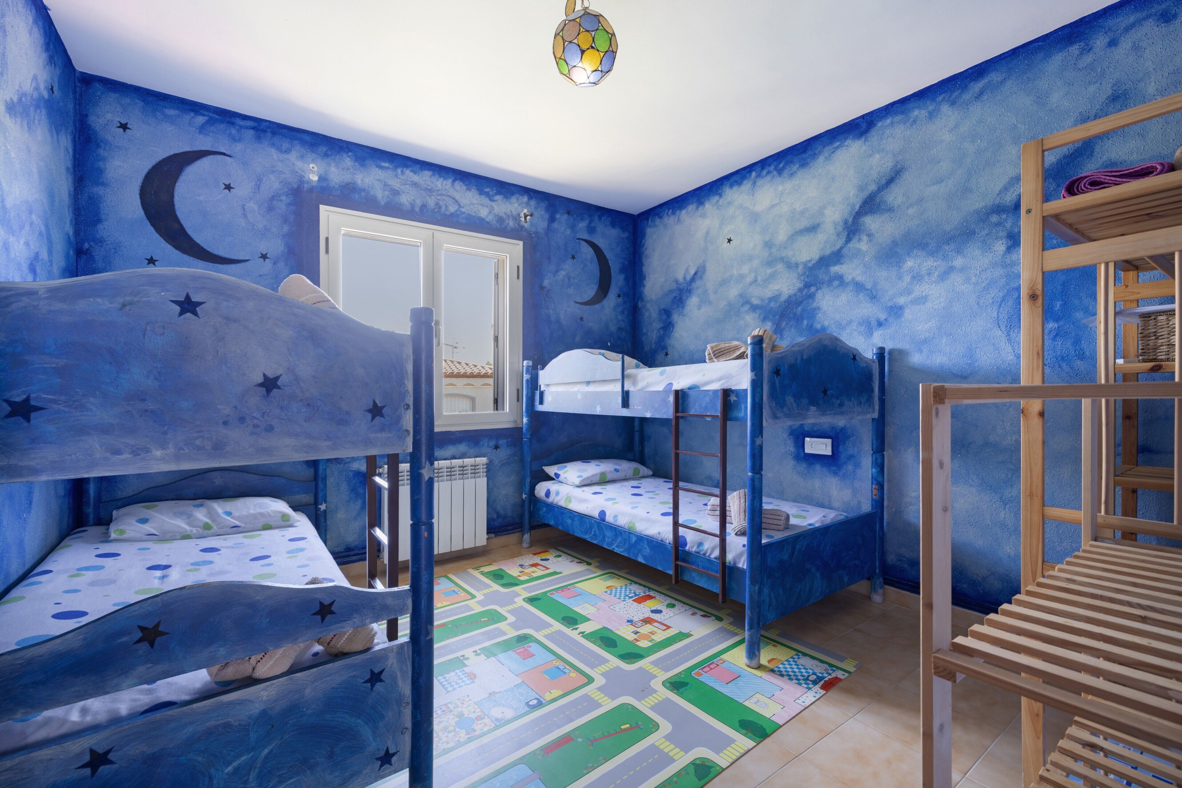 Une chambre avec des lits superposés, une fenêtre et un motif mural représentant des étoiles.