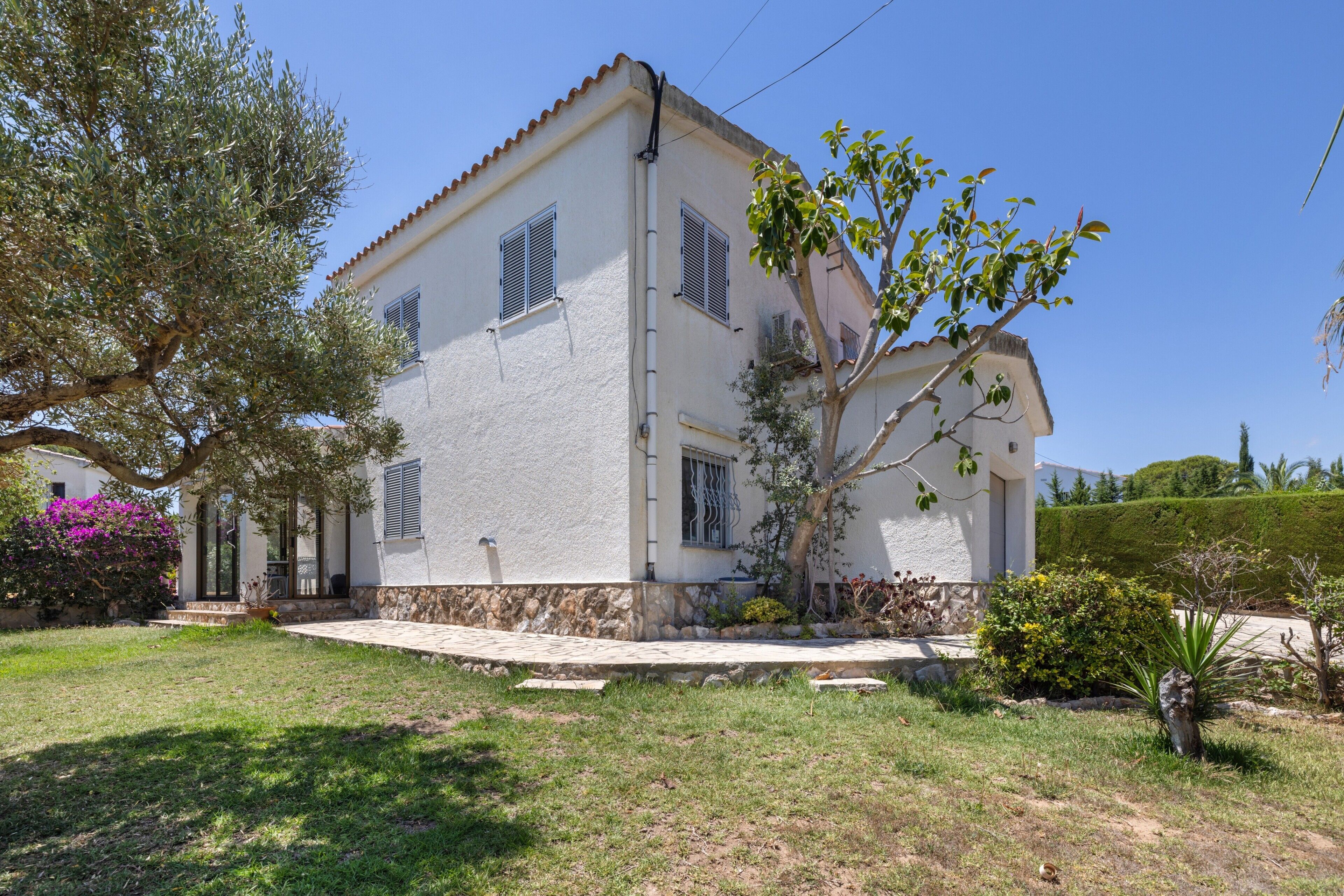 Une maison à deux étages, avec une base en pierre, des murs blancs et un toit recouvert de tuiles.