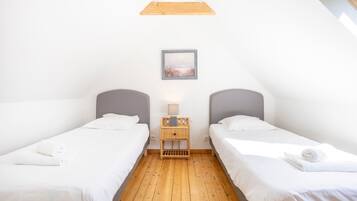 Een slaapkamer met twee bedden, een nachtkastje met een lamp, en een lijst met een afbeelding aan de muur.