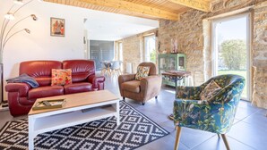 A living room with a red leather sofa, a brown armchair, a patterned rug, and a wooden ceiling.