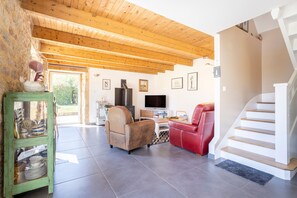 A living room with a fireplace, a television, a red chair, and a staircase.