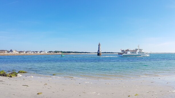 A coastal scene with a boat, a lighthouse, and a beach.