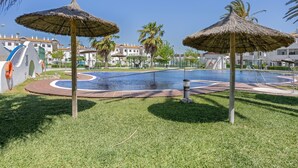 A pool area with thatched umbrellas, palm trees, and a circular water feature.