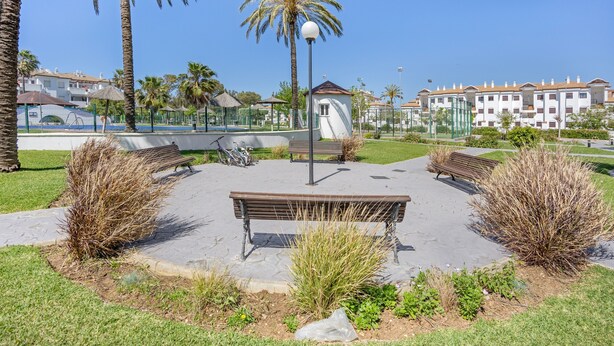 A park with benches, a lamp post, and a playground.