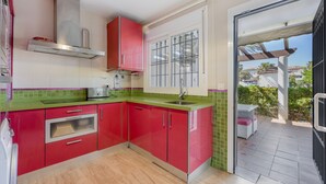 A kitchen with red cabinets, a green countertop, and a window with a view of the outside.
